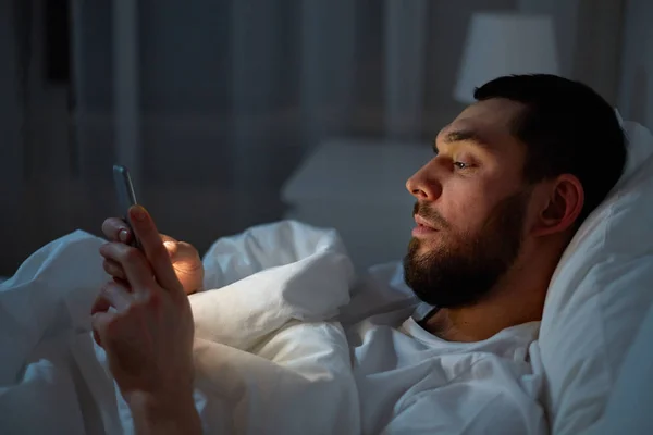 智能手机在床上的男人 — 图库照片