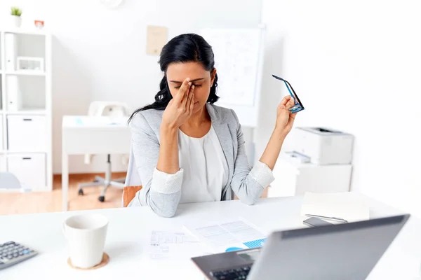 Businesswoman rubbing tired eyes at office — Stock Photo, Image