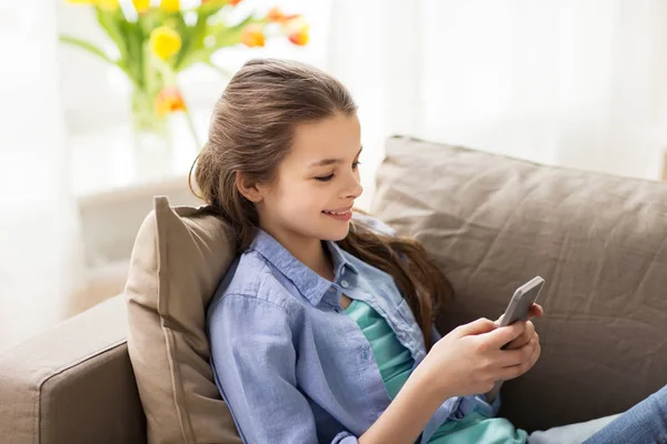 Sorridente ragazza sms su smartphone a casa — Foto Stock