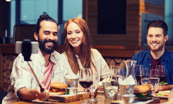 Friends taking selfie by smartphone at restaurant — Stock Photo, Image