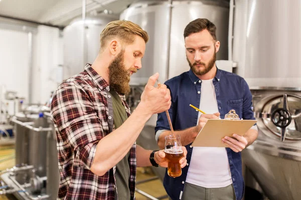 Чоловіки з піпеткою тестують крафтове пиво на пивоварні — стокове фото