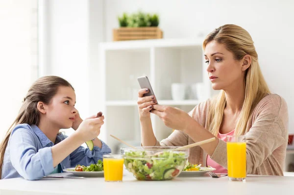 Triest meisje kijken naar haar moeder met smartphone — Stockfoto