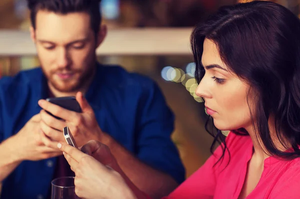 Pareja con smartphones cenando en el restaurante — Foto de Stock