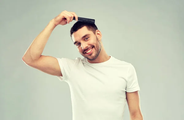 Glücklicher Mann, der Haare mit Kamm über Grau streicht — Stockfoto