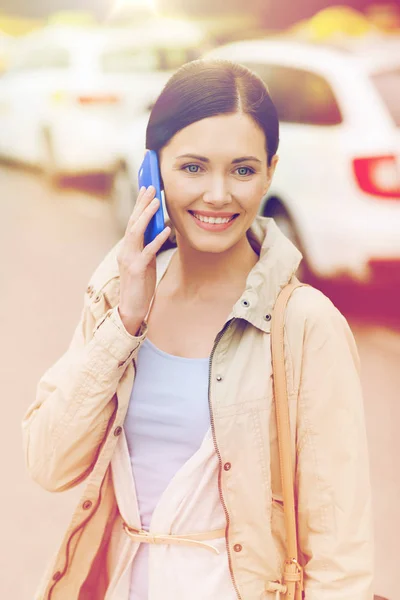 Lachende vrouw met smartphone over taxi in stad — Stockfoto