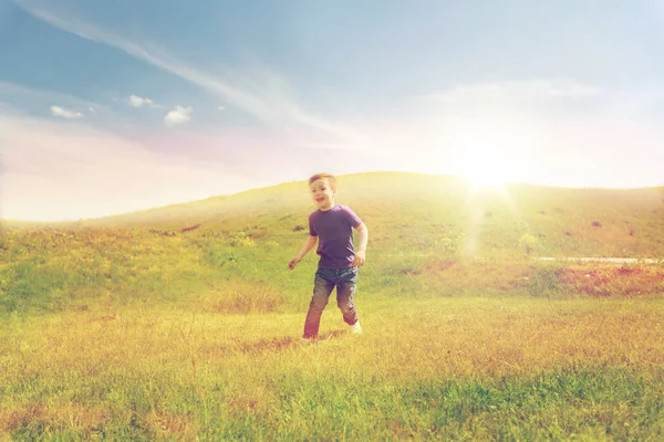 Happy little boy running on green field outdoors — Stock Photo, Image