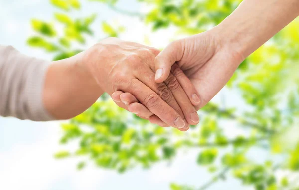 Nahaufnahme einer Seniorin und einer jungen Frau beim Händchenhalten — Stockfoto