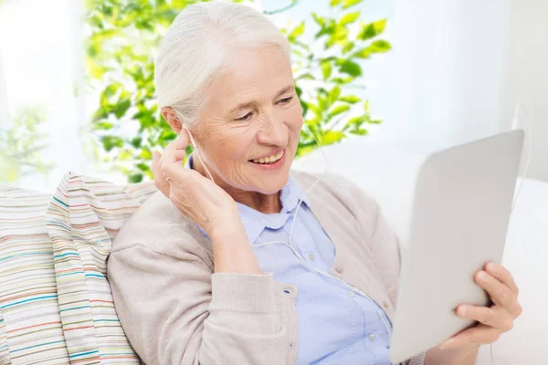 Starší žena s tablet pc a sluchátka doma — Stock fotografie