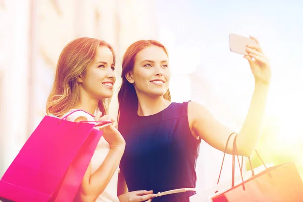 Mulheres felizes com sacos de compras e smartphone — Fotografia de Stock