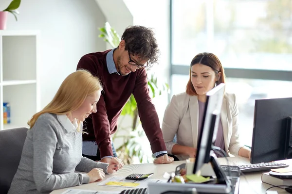 Feliz equipo de negocios con calculadora en la oficina — Foto de Stock