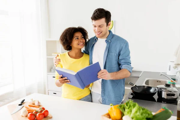 Ευτυχισμένο ζευγάρι με το μαγείρεμα στο σπίτι βιβλίο κουζίνα — Φωτογραφία Αρχείου