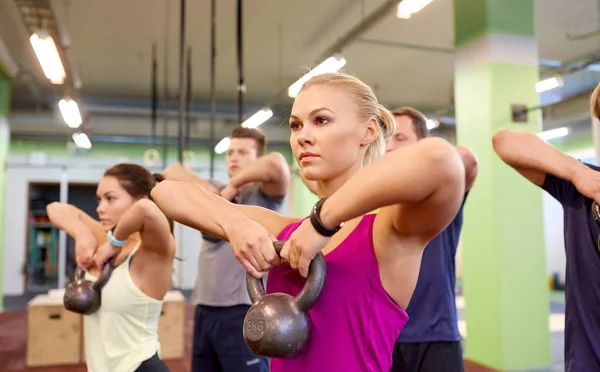 Gruppe von Menschen mit Kettlebells, die im Fitnessstudio trainieren — Stockfoto