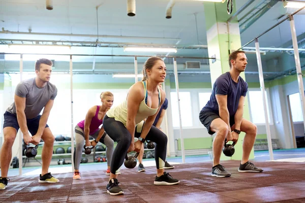 Gruppe von Menschen mit Kettlebells, die im Fitnessstudio trainieren — Stockfoto