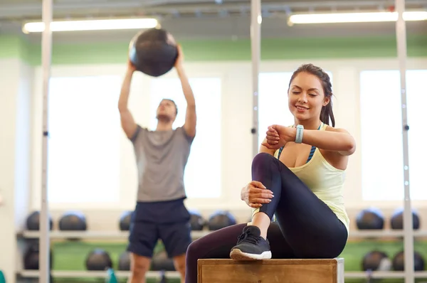 Man and woman with ball and fitness tracker in gym — Stock Photo, Image