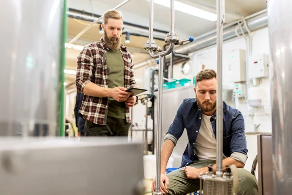 Мужчины с планшетным ПК на ремесленном пивоваренном фильтре — стоковое фото