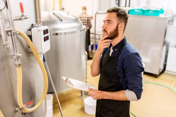 Hombre con portapapeles en cervecería artesanal o fábrica de cerveza — Foto de Stock