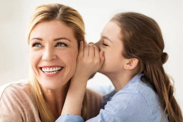 Glückliches Mädchen flüstert ihrer Mutter Geheimnis zu — Stockfoto
