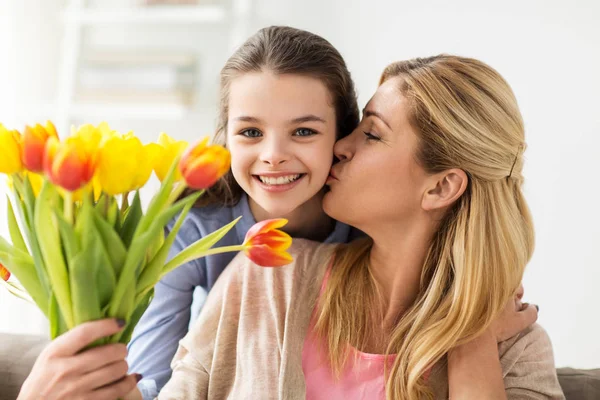 Menina feliz dando flores para a mãe em casa — Fotografia de Stock