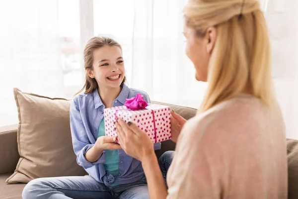 Menina dando presente de aniversário para a mãe em casa — Fotografia de Stock