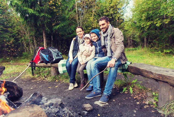 Happy family sitting on bench at camp fire — Stock Photo, Image