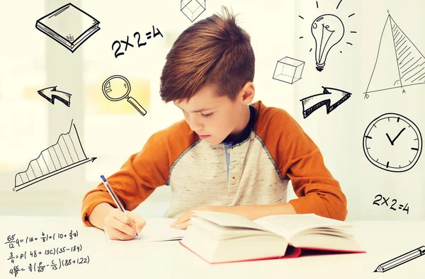 Студентський хлопчик з книжковим написанням на блокноті вдома — стокове фото