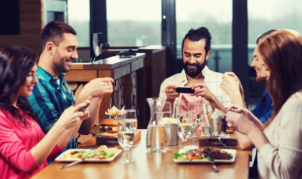 Amigos felizes tirando fotos de comida no restaurante — Fotografia de Stock