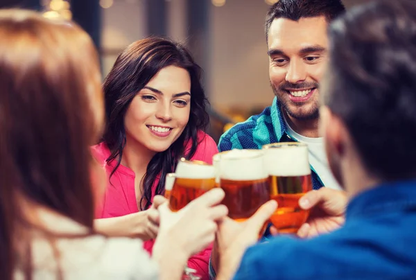 Друзья пьют пиво и звонят в стаканы в пабе — стоковое фото