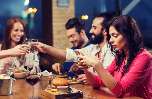 Donna con smartphone e amici al ristorante — Foto Stock
