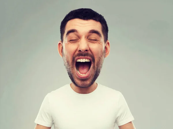 Szalony krzyczący człowiek w t-shirt na szarym tle — Zdjęcie stockowe