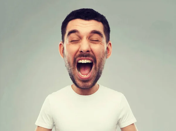 Verrückter schreiender Mann im T-Shirt vor grauem Hintergrund — Stockfoto