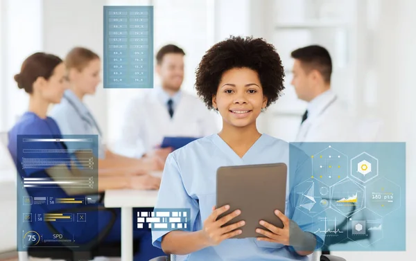 Happy doctor with tablet pc over team at clinic — Stock Photo, Image