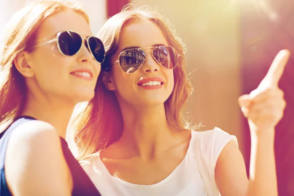 Mujeres felices en gafas de sol señalando con el dedo al aire libre — Foto de Stock