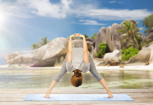 Mujer haciendo yoga de piernas anchas curva hacia adelante en la playa — Foto de Stock