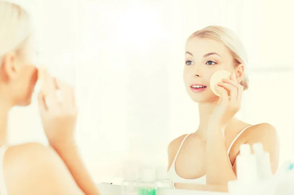 Mujer joven lavando la cara con esponja en el baño — Foto de Stock