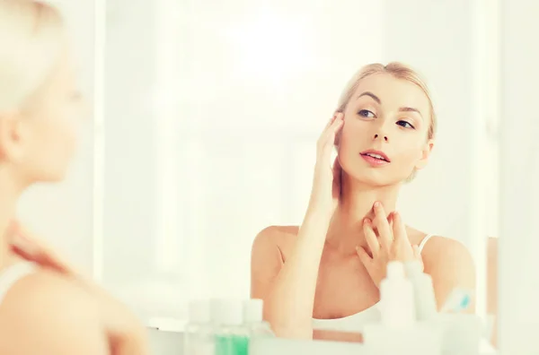 Happy young woman looking to mirror at bathroom — Stock Photo, Image