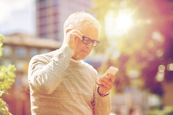 Hombre mayor mensaje de texto en el teléfono inteligente en la ciudad — Foto de Stock