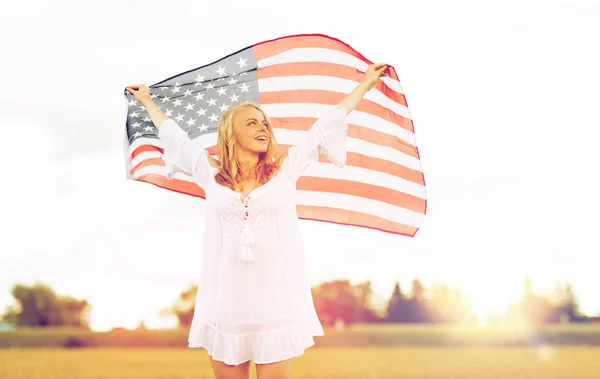 Mulher feliz com bandeira americana no campo de cereais — Fotografia de Stock