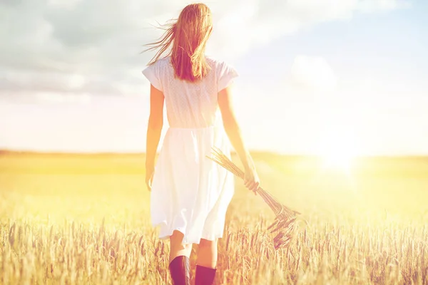 Giovane donna con spighette di cereali che camminano sul campo — Foto Stock