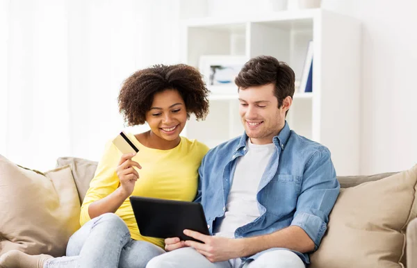 Casal com tablet pc e cartão de crédito em casa — Fotografia de Stock