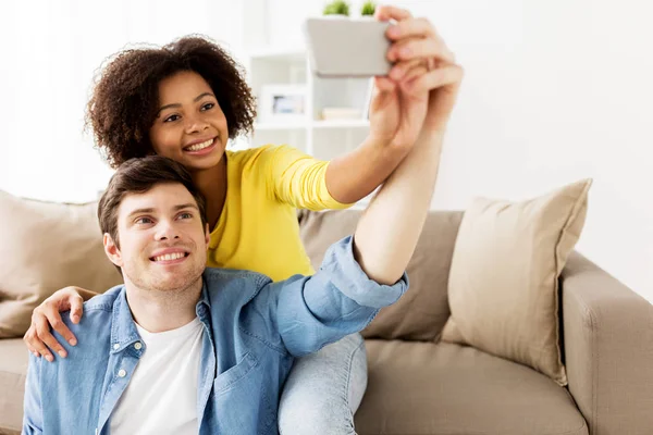 Счастливая пара со смартфоном делает селфи дома — стоковое фото
