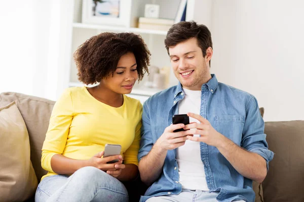 Casal feliz com smartphones em casa — Fotografia de Stock