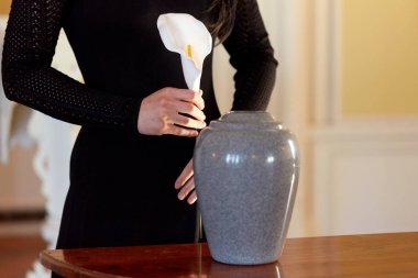 woman with cremation urn at funeral in church clipart