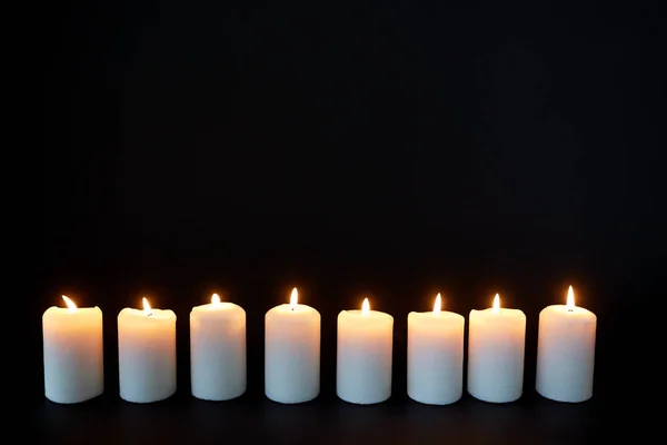 Свічки, що горять у темряві над чорним тлом — стокове фото