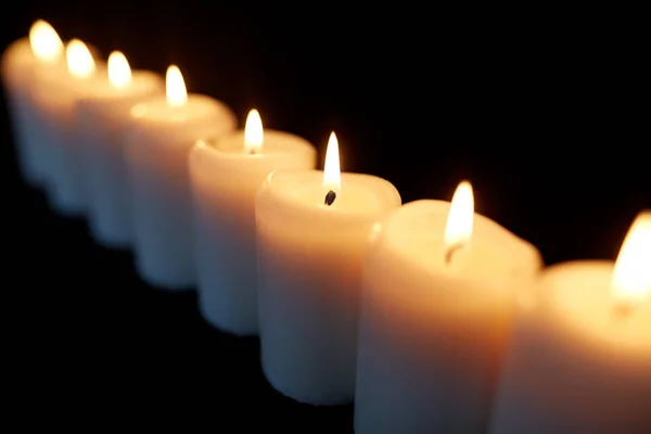 Candele che bruciano nel buio su sfondo nero — Foto Stock