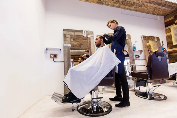 Homem e barbeiro cortando cabelo na barbearia — Fotografia de Stock