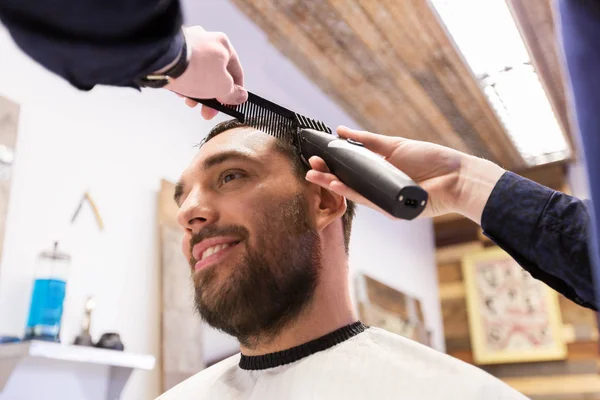 Uomo e barbiere con trimmer taglio capelli al salone — Foto Stock