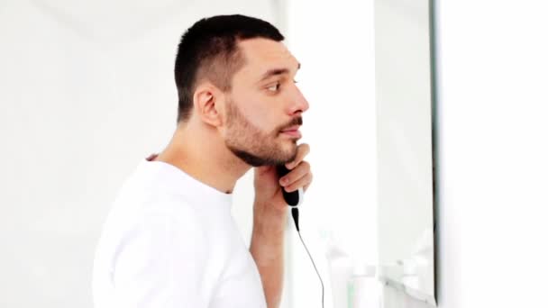 Человек бритья бороду с триммером в ванной комнате — стоковое видео