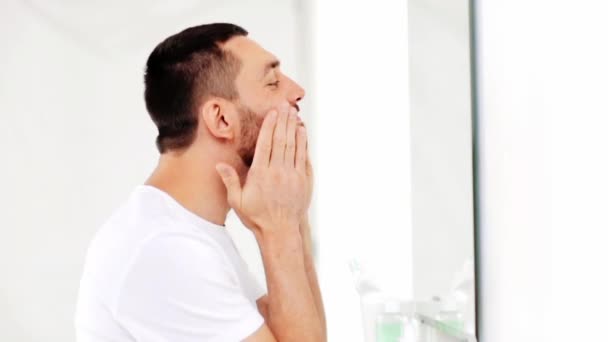 Happy man applying aftershave to face at bathroom — Stock Video