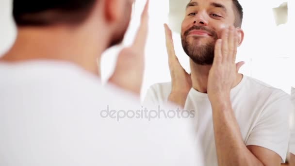 Счастливый мужчина после бритья должен смотреть в лицо в ванной — стоковое видео