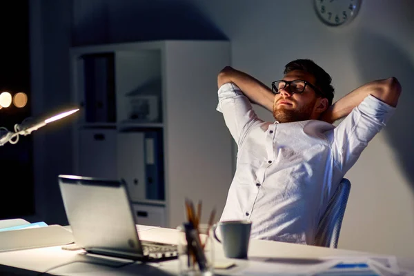Uomo con computer portatile che si estende in ufficio notturno — Foto Stock